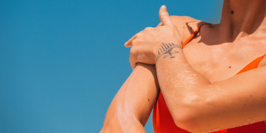 mulher passando protetor solar no braço